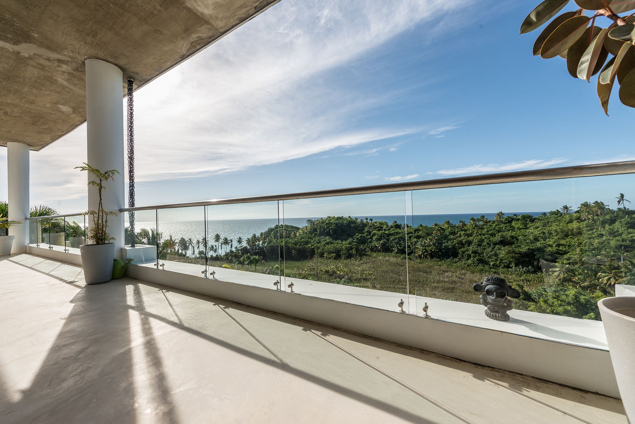 A balcony with a clear view of the sea and greenery.