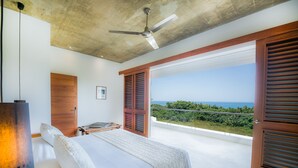 A bedroom with a large bed, a ceiling fan, and a view of the ocean. - Casa Phil (Las Terrenas)