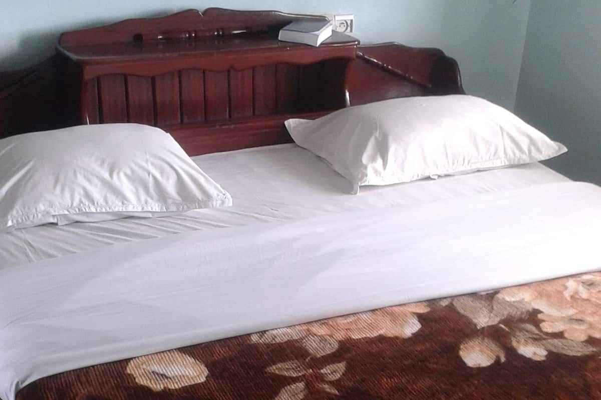 A bed with white linens and a brown floral bedspread.