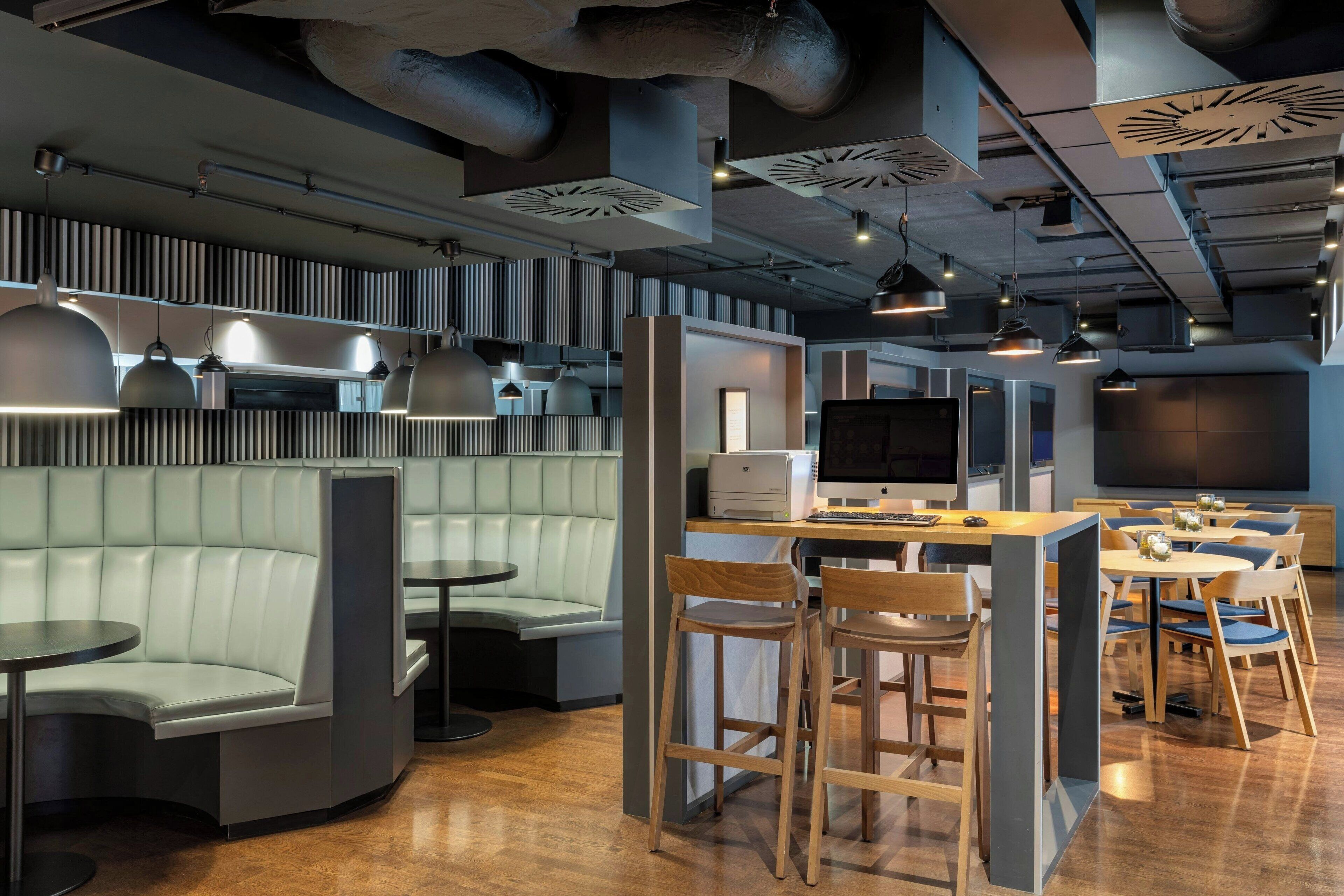 A modern restaurant with a bar area, seating arrangements, and a large screen.