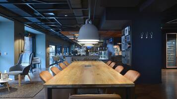 Una sala de conferencias moderna con una larga mesa de madera, sillas de cuero y una lámpara colgante grande.