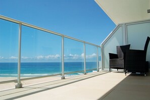 A balcony with a glass railing overlooking the ocean, featuring two wicker chairs. - Praia del Rey Golf and Beach Resort The Beachfront (Obidos)