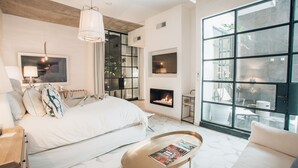 Un dormitorio moderno con cama, mesita de noche, lámpara y chimenea.