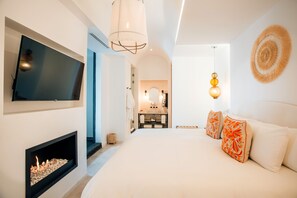 A modern bedroom with a large bed, a TV mounted on the wall, and a fireplace. - LOtel-Casa Arca (San Miguel de Allende)