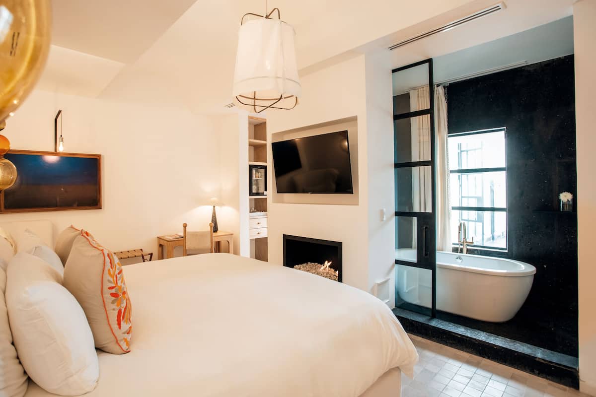 Un dormitorio moderno con una cama grande, televisión, chimenea y bañera.