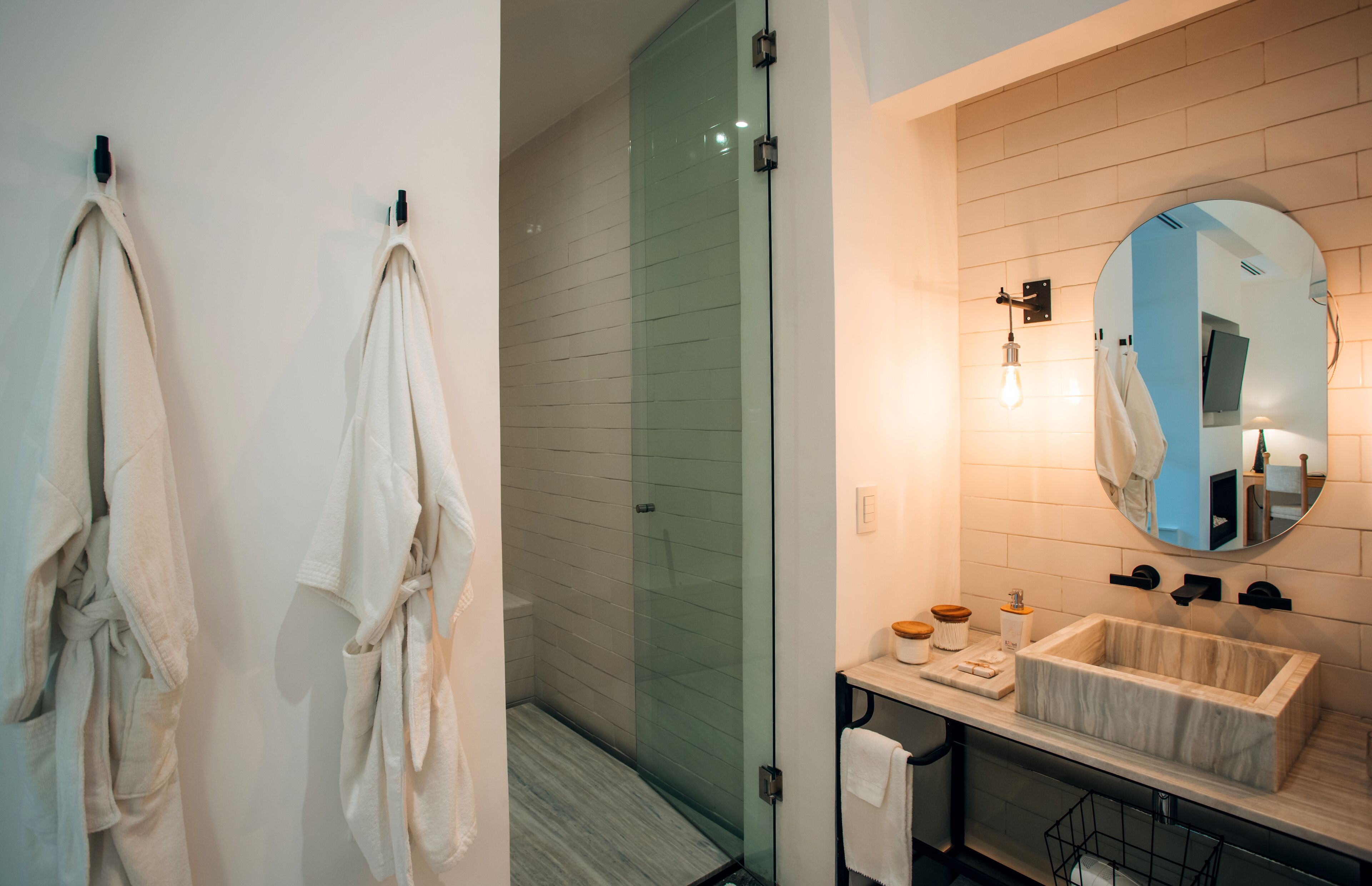 A modern bathroom with a glass shower enclosure, a marble sink, and a large mirror.