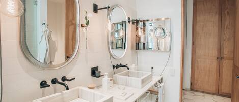 Un baño moderno con dos lavamanos, espejos amplios y un armario de madera.