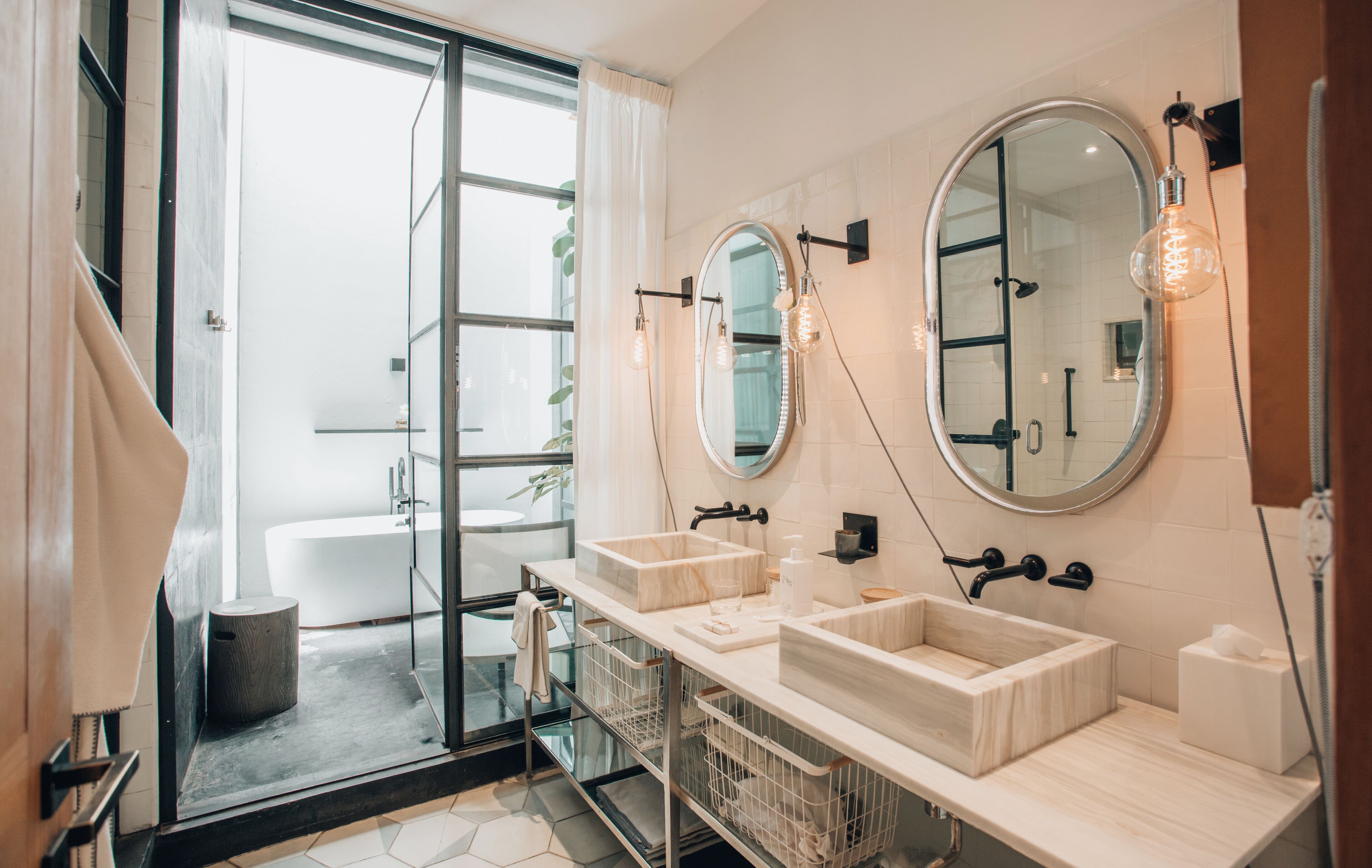 A modern bathroom with two sinks, a large mirror, and a glass shower enclosure.