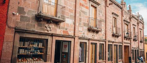 Una hilera de edificios históricos con fachadas de piedra, puertas de madera y balcones.