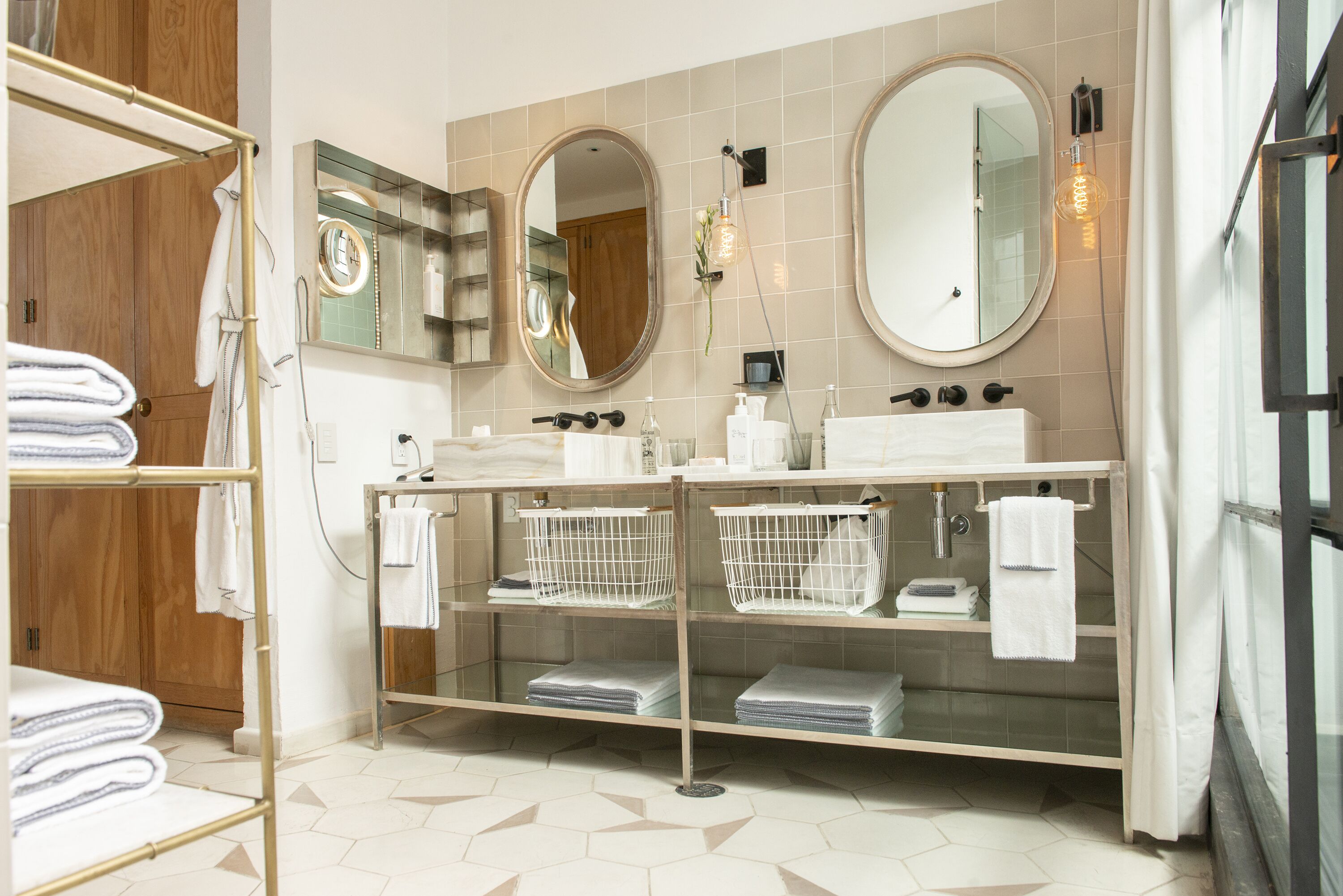 A modern bathroom with two sinks, a large mirror, and a towel rack.