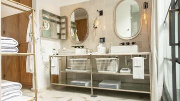 A modern bathroom with two sinks, a large mirror, and a towel rack.