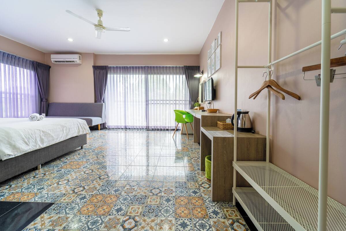 Quarto de hotel com uma cama, uma escrivaninha, uma cadeira e uma televisão.