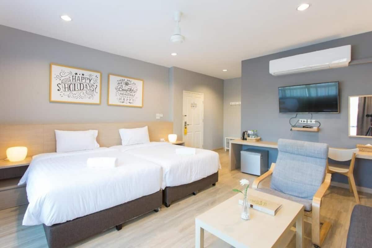 Quarto de hotel com duas camas, uma escrivaninha, uma cadeira, ar condicionado e televisão.