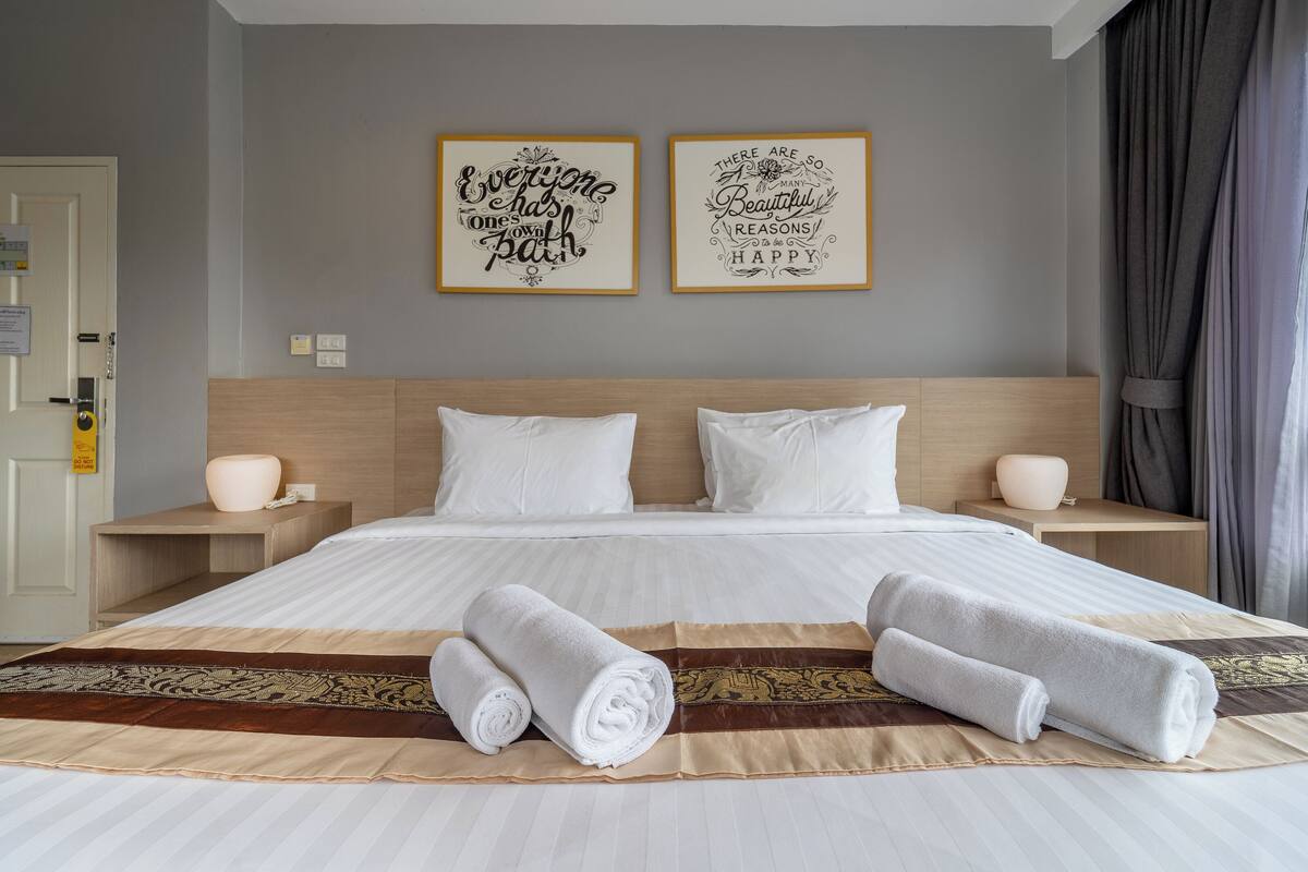 Quarto de hotel com uma cama grande, duas mesas de cabeceira e dois quadros pendurados na parede.
