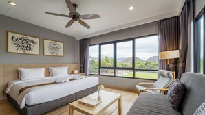 Una habitación de hotel moderna con una cama grande, un sofá, una mesita de centro y vistas al exterior.