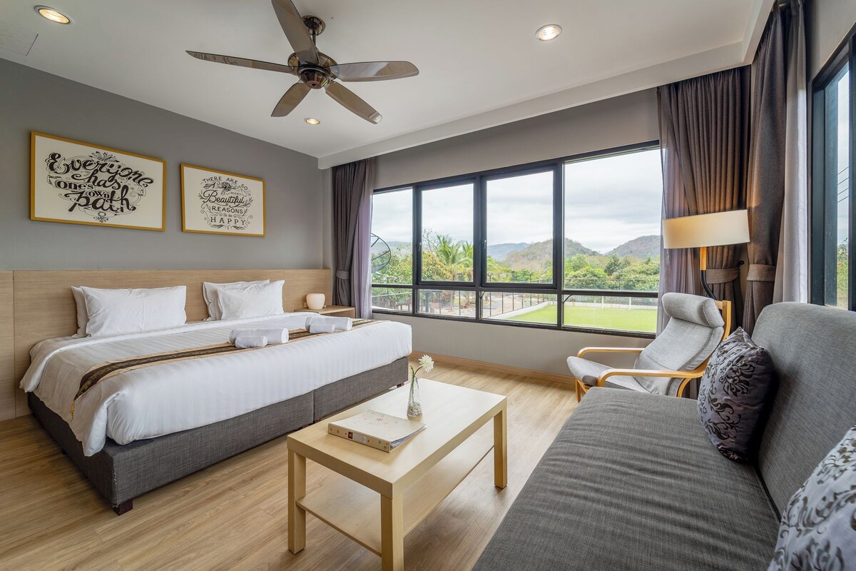 A hotel room with a bed, a sofa, a coffee table, and a view of the outdoors.