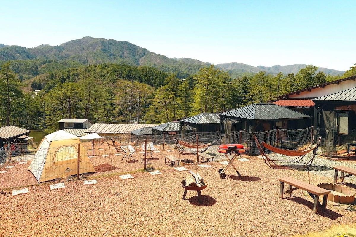 A campsite with tents, a barbecue grill, and a hammock.