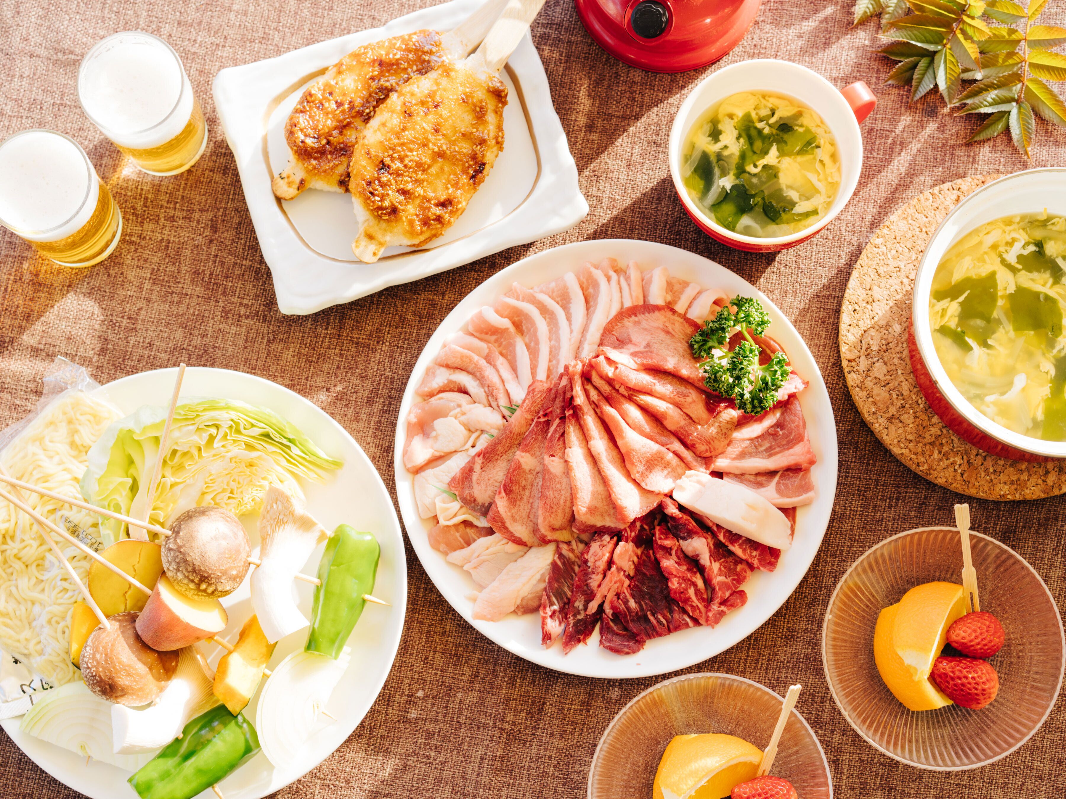 Una variedad de platos con carne, verduras y fruta, dispuestos sobre una mesa.