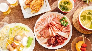 Una variedad de platos con carne, verduras y fruta, dispuestos sobre una mesa.