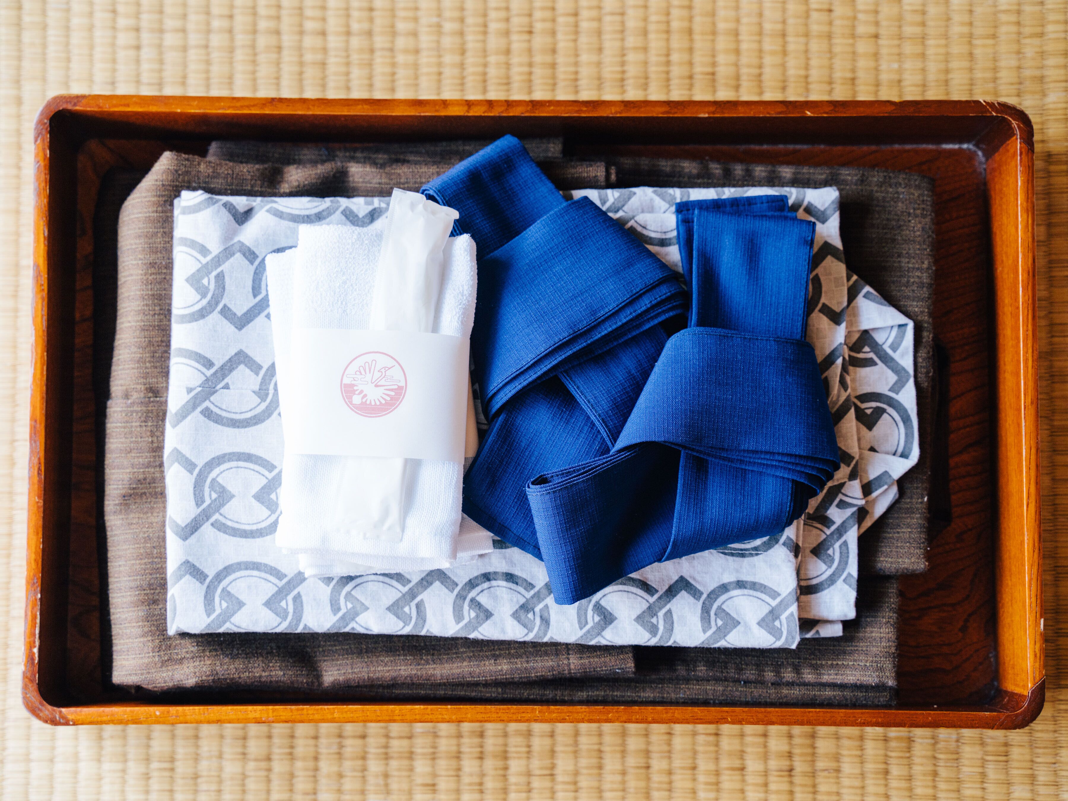 A wooden tray with folded towels and a patterned cloth.