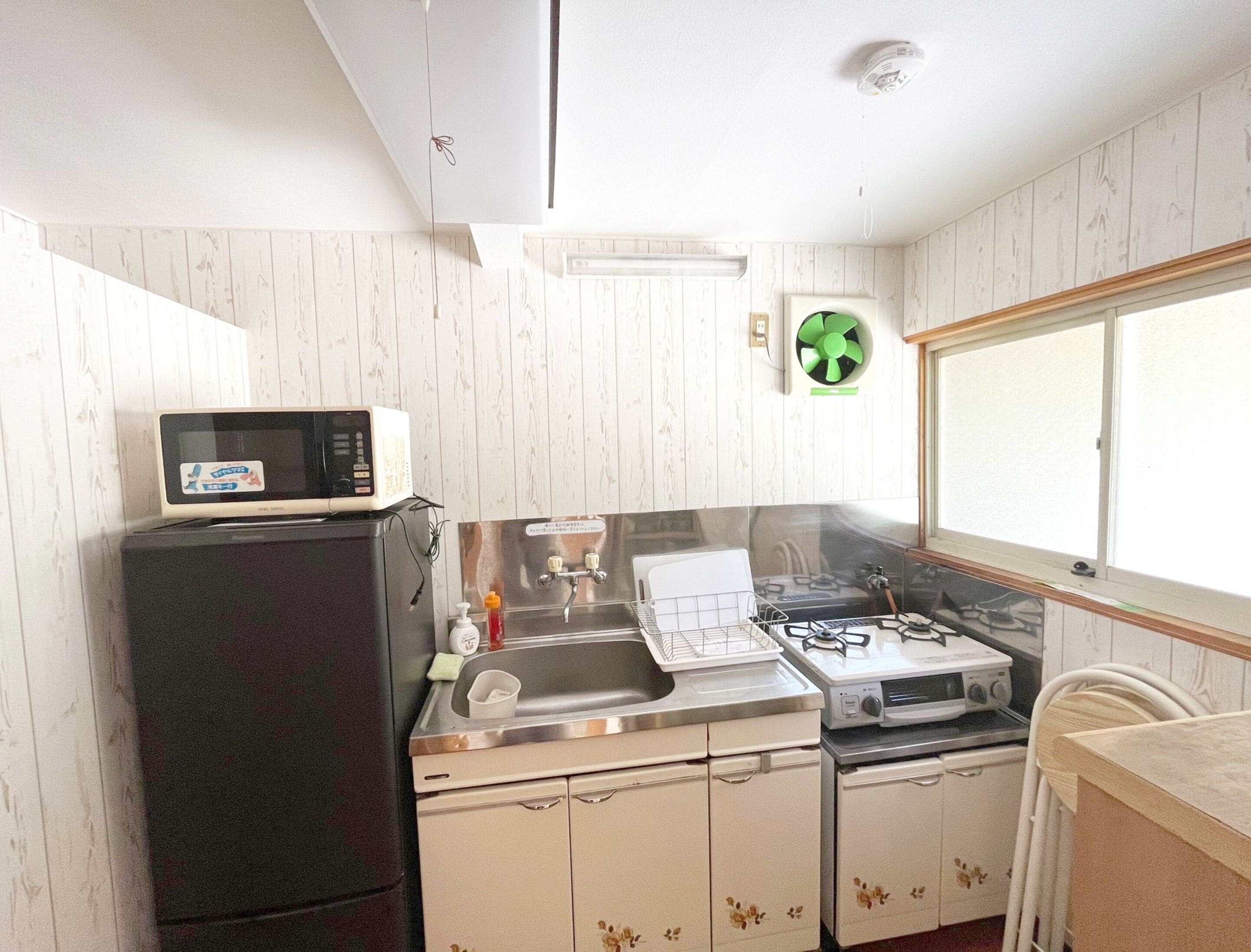 Une cuisine compacte équipée d’un four à micro-ondes, d’un évier, d’une cuisinière et de placards.