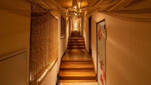 Un escalier avec des marches en bois menant vers le haut, flanqué de murs à motifs texturés et d’une porte ornée de motifs floraux.