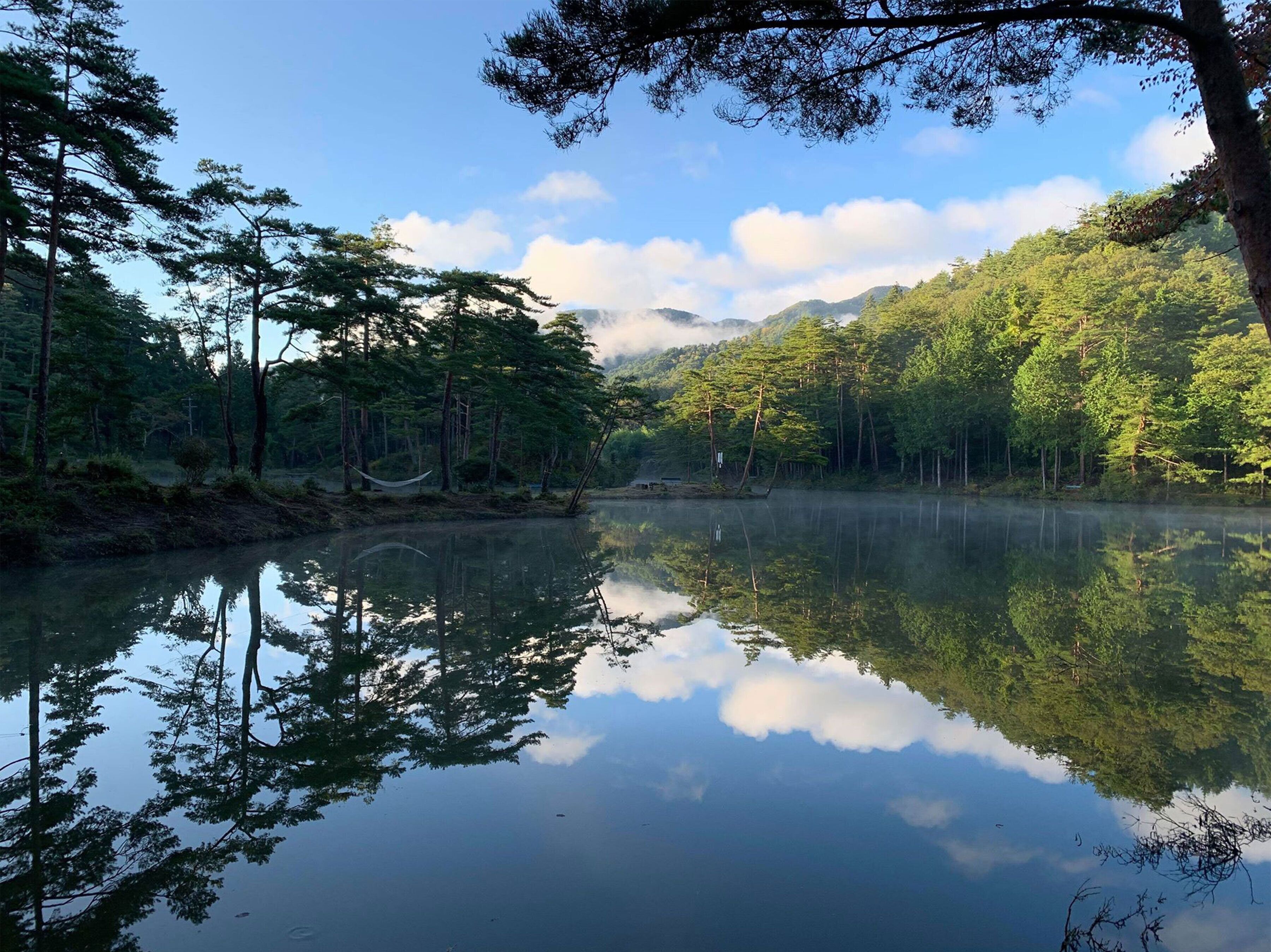 A serene lake surrounded by dense forest and mountains.