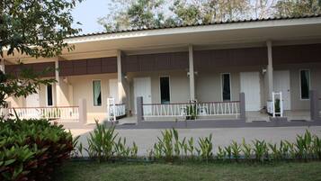 A building with a covered porch, multiple doors, and a fenced area with plants.