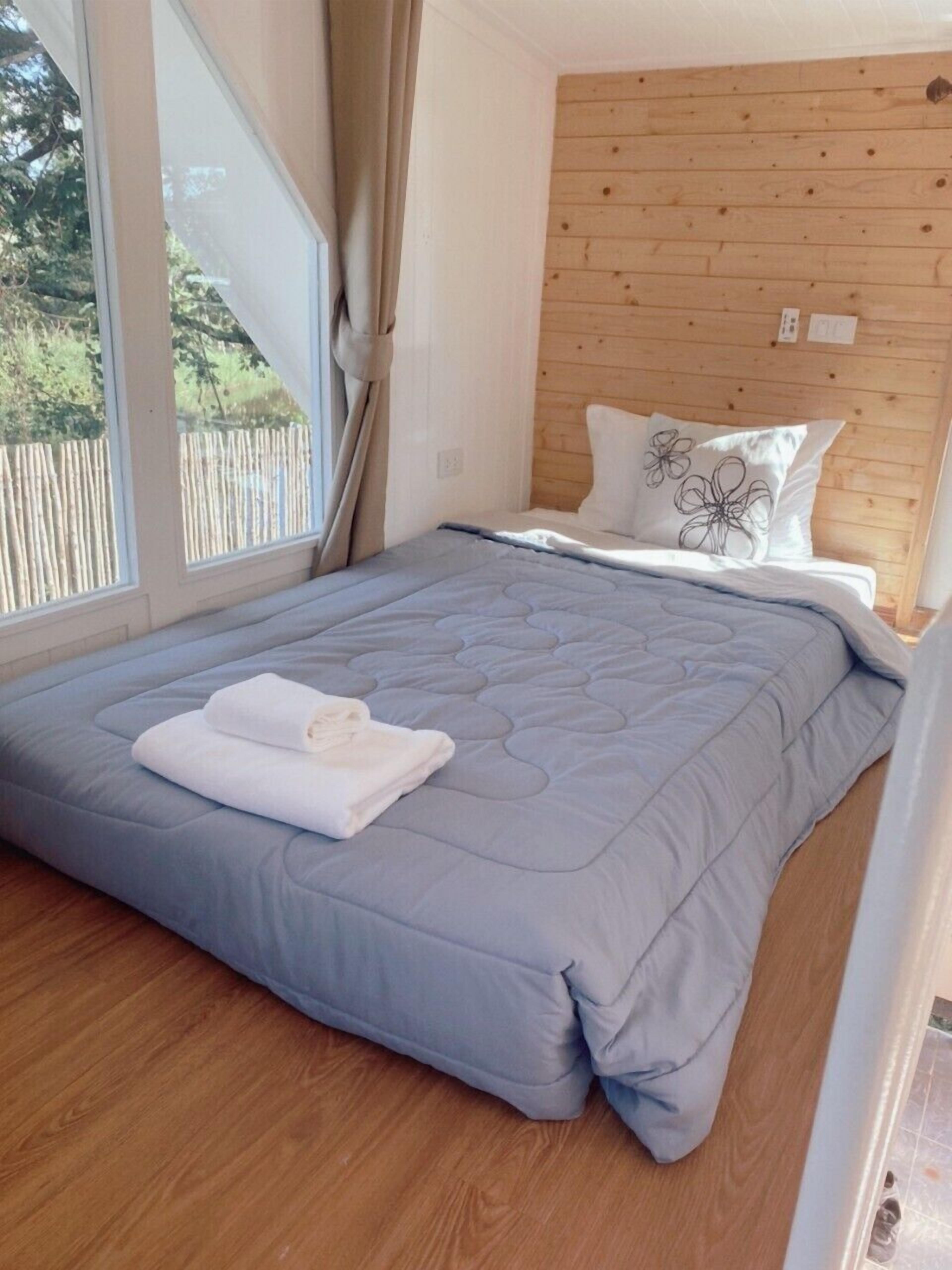 Un dormitorio con una cama grande, cabecera de madera y vista a una valla de madera.