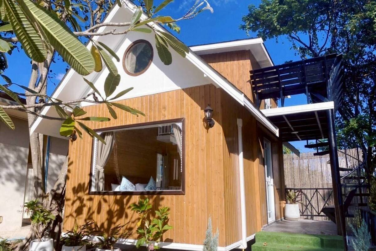 A wooden house with a balcony, a window, and potted plants.