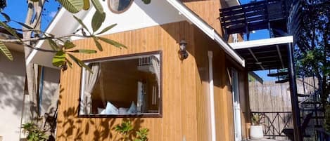 A wooden house with a balcony, a window, and potted plants.