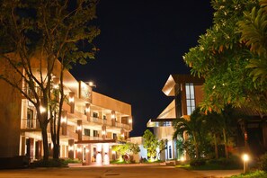 Un hotel de diverses plantes amb balcons il·luminats i una entrada ben il·luminada.