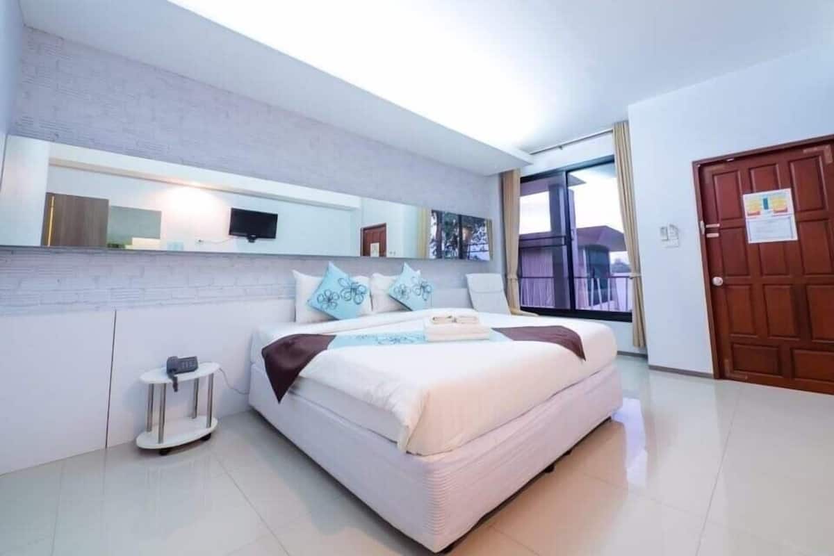 A modern bedroom with a bed, a TV, a mirror, and a door.