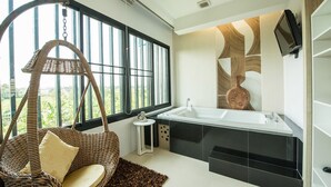 A modern bathroom with a large window, a hanging chair, a bathtub, and a small table. - Panlaan Boutique Resort (Nong Khai)