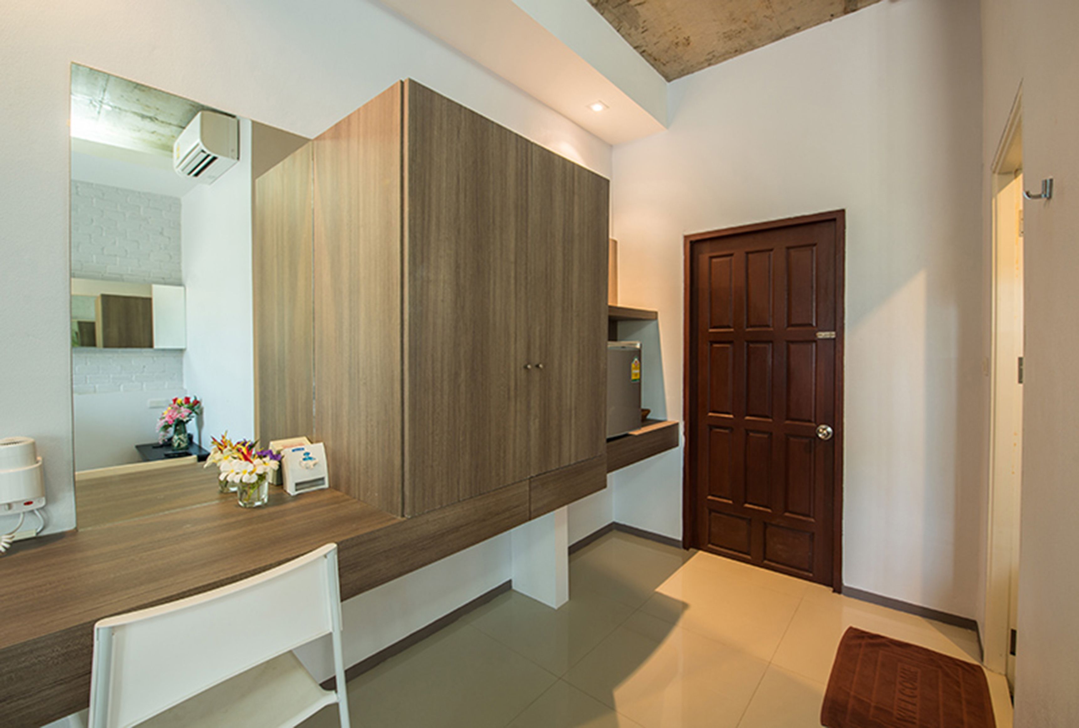 A modern bathroom with a wooden vanity, a large mirror, and a wooden door.