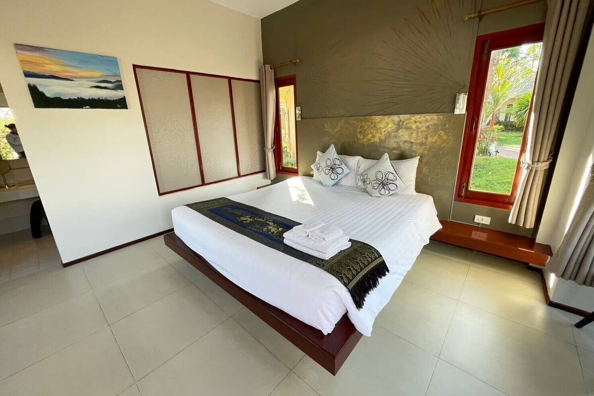 A bedroom with a bed, a window, a painting, and a sliding door.