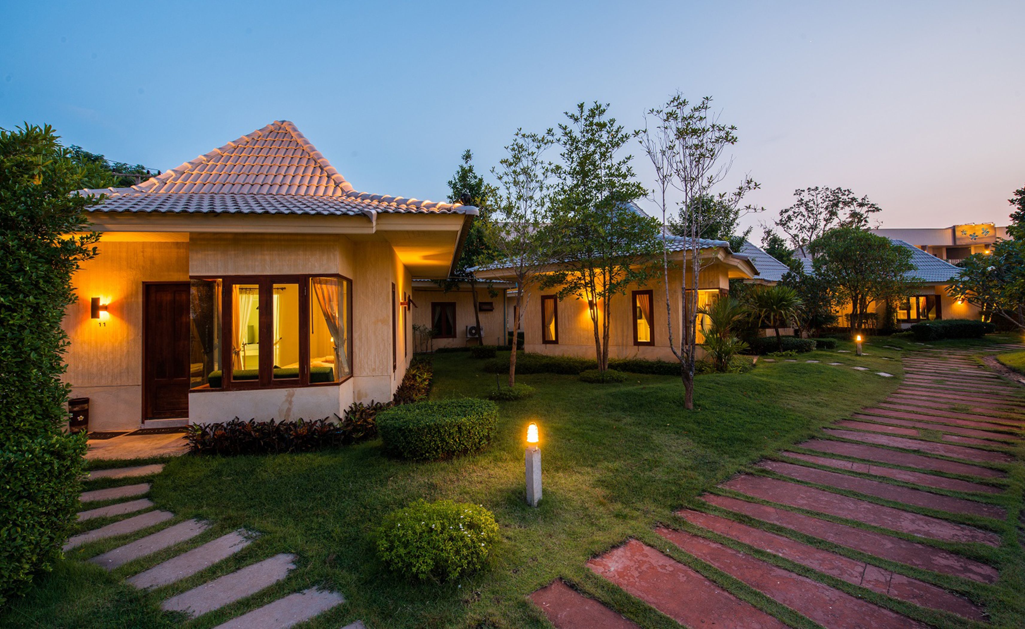 Un resort con varias villas, cada una con techo de tejas, césped cuidado y un camino hacia la entrada.