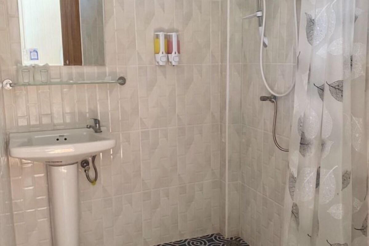 Un baño con lavamanos, espejo, ducha y cortina de ducha estampada.