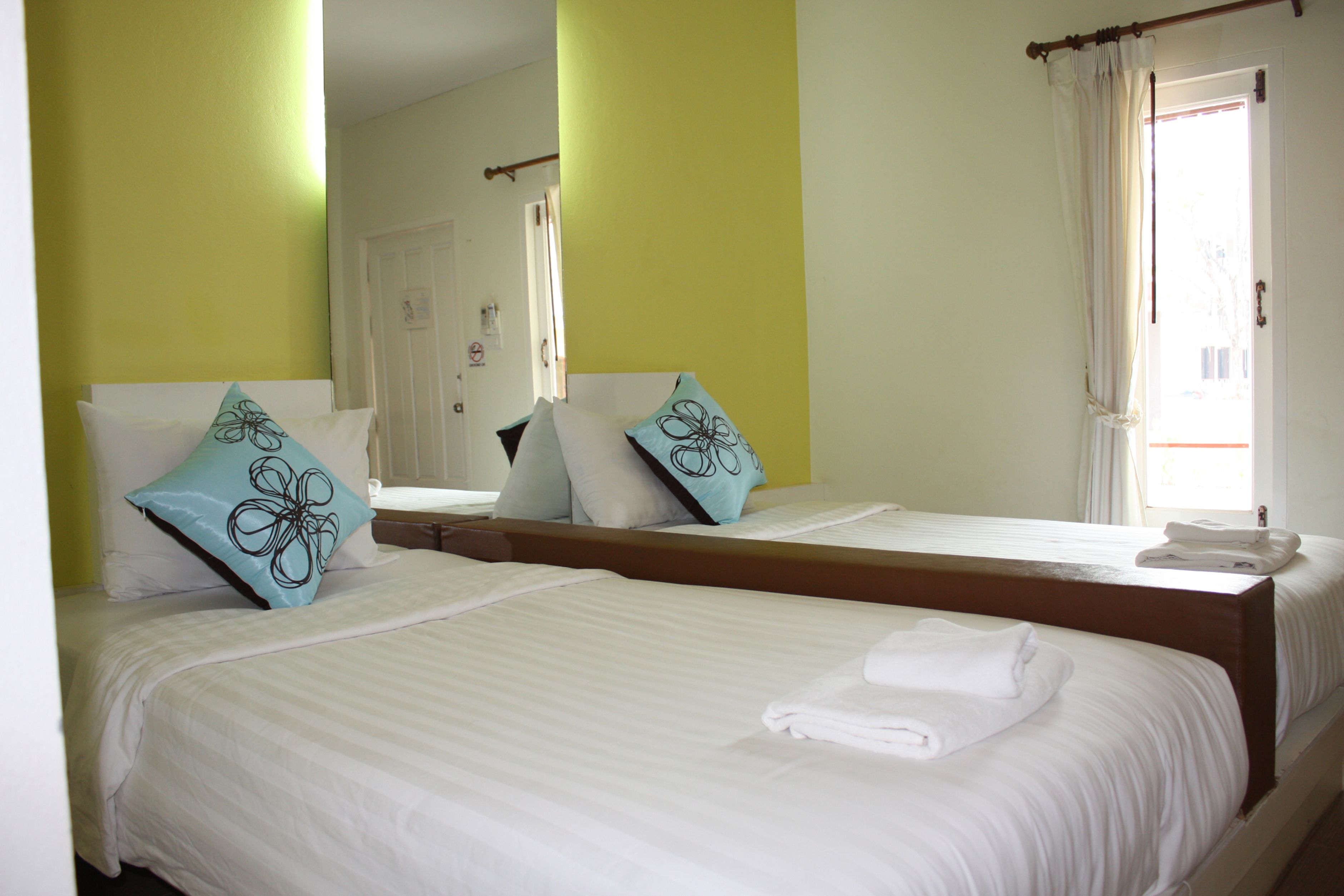 A hotel room with two beds, each with white linens and decorative pillows.