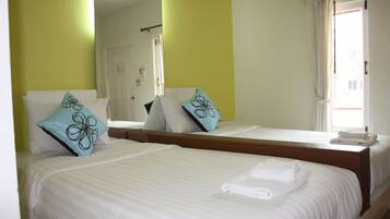 A hotel room with two beds, each with white linens and decorative pillows.