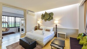 A modern hotel room with a large bed, bedside lamps, a small table, a sofa, and a view of greenery through the window. - Panlaan Boutique Resort (Nong Khai)