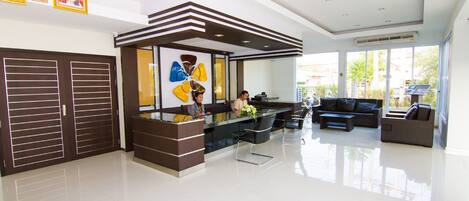 A modern reception area with a reception desk, seating, and a large window offering a view of the outdoors.