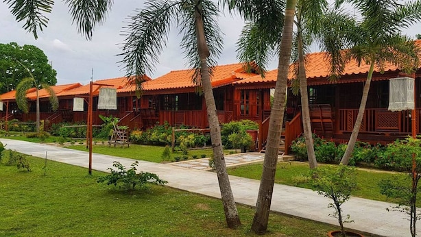 A row of wooden bungalows with tiled roofs, surrounded by palm trees and a well-maintained garden. - Bu-Nga Resort (Koh Lipe)