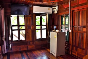 A wooden-paneled room with a built-in air conditioning unit, a refrigerator, and a window with curtains. - Bu-Nga Resort (Koh Lipe)