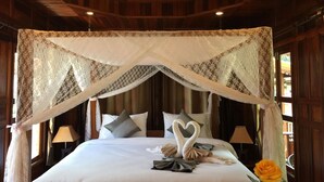 A hotel room with a canopy bed, pillows, a heart-shaped towel arrangement, and a single rose. - Bu-Nga Resort (Koh Lipe)
