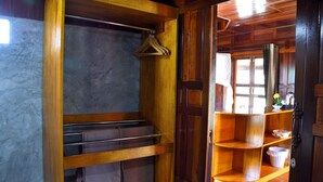 A wooden interior with a hanging rack, shelves, and a door leading to another room. - Bu-Nga Resort (Koh Lipe)