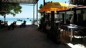A beachside restaurant with outdoor seating, a covered area, and a view of the sea. - Bu-Nga Resort (Koh Lipe)