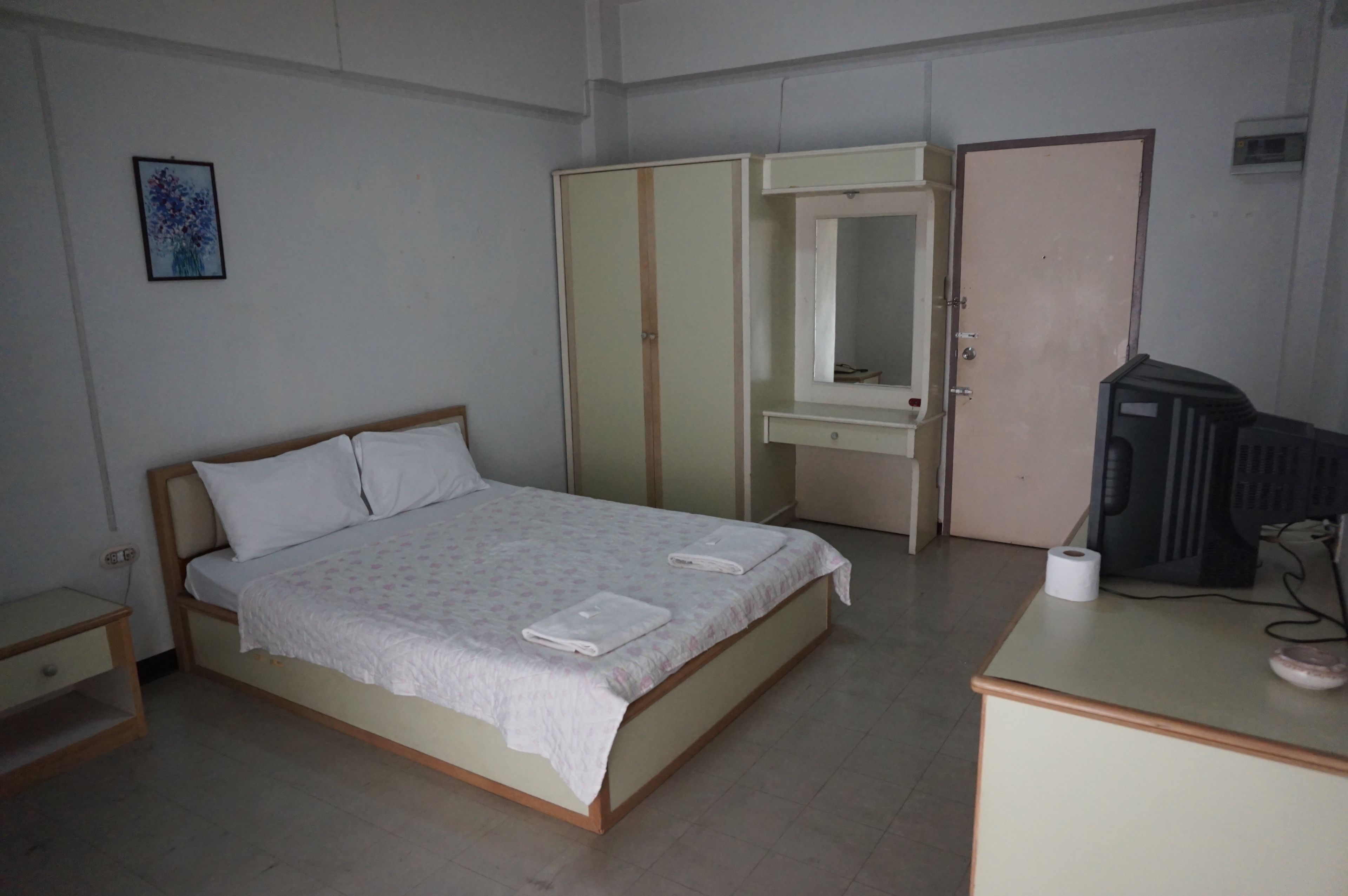 Ein Schlafzimmer mit Bett, Nachttisch, Kleiderschrank, Spiegel und Fernseher.