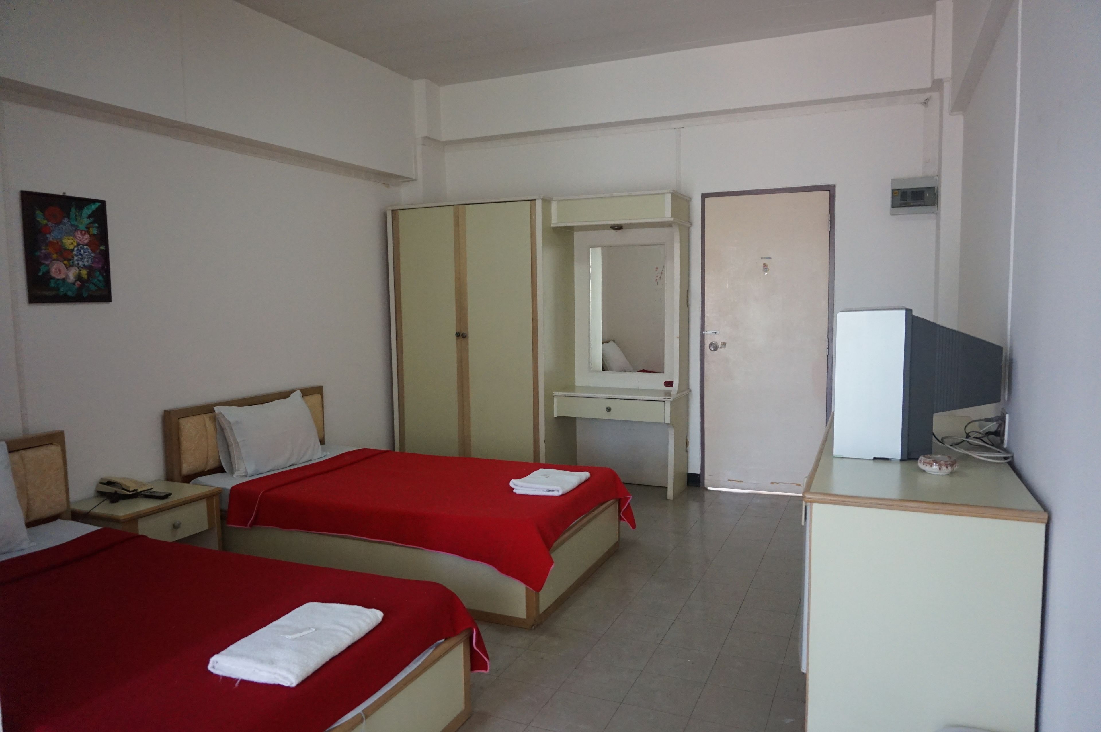 A hotel room with two beds, a desk with a computer, a mirror, and a small cabinet.