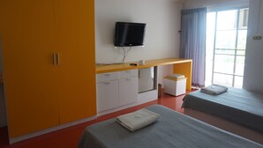 A hotel room with a bed, a TV mounted on the wall, a wardrobe, and a window with curtains.